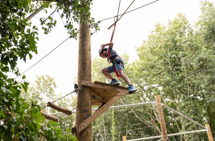 young boy on an aerial assault course high in the treetops