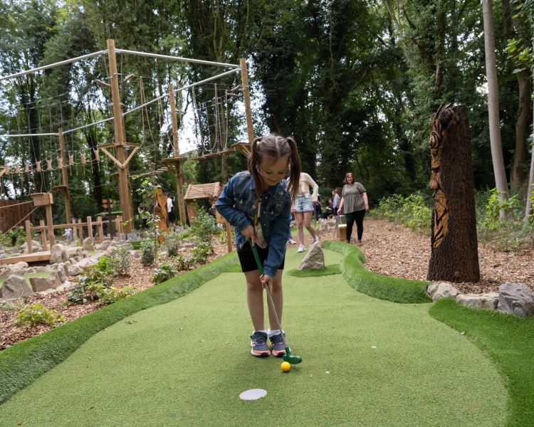 young boy playing adventure golf in woodland