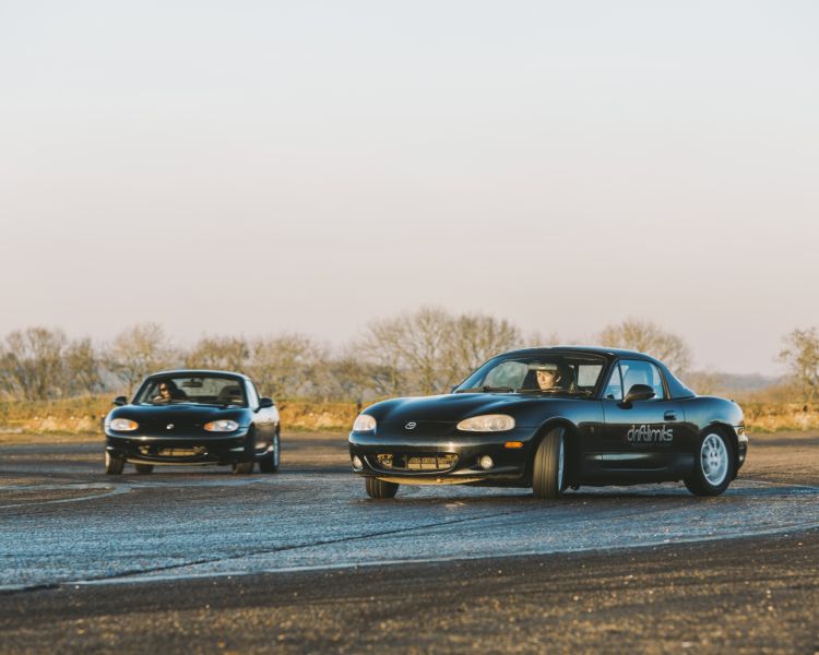 2 black sports cars on a race track as part of a drifting experience