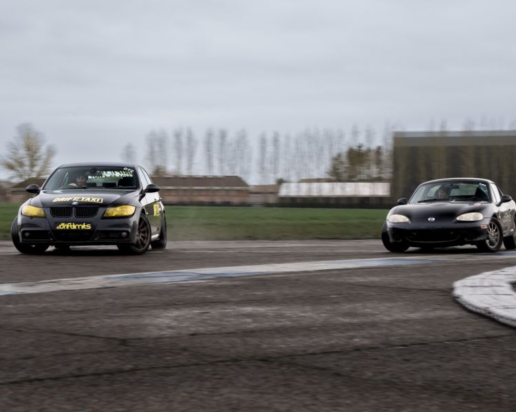 2 black sports cars on a race track as part of a drift battle experience day