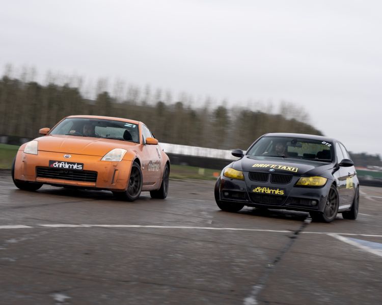 an orange sportscar and a black sportscar side by side on a race track as part of a drift battle nissan 350z driving experience day