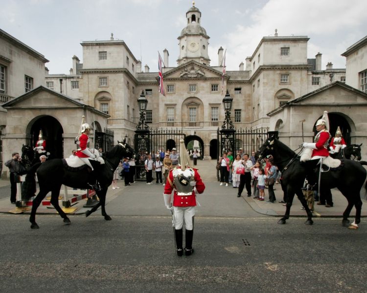 a view of the outside of the household cavalry museum with people watching guards on horseback