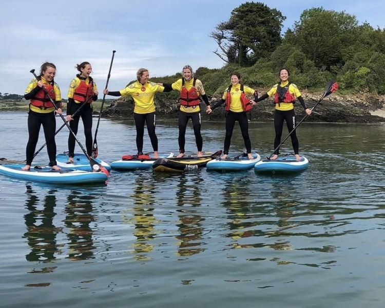 group of women standing on paddle boards