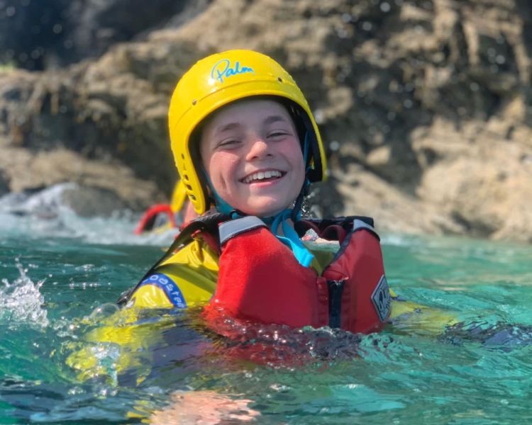 Young boy in the sea wearing a life jacket and helmet