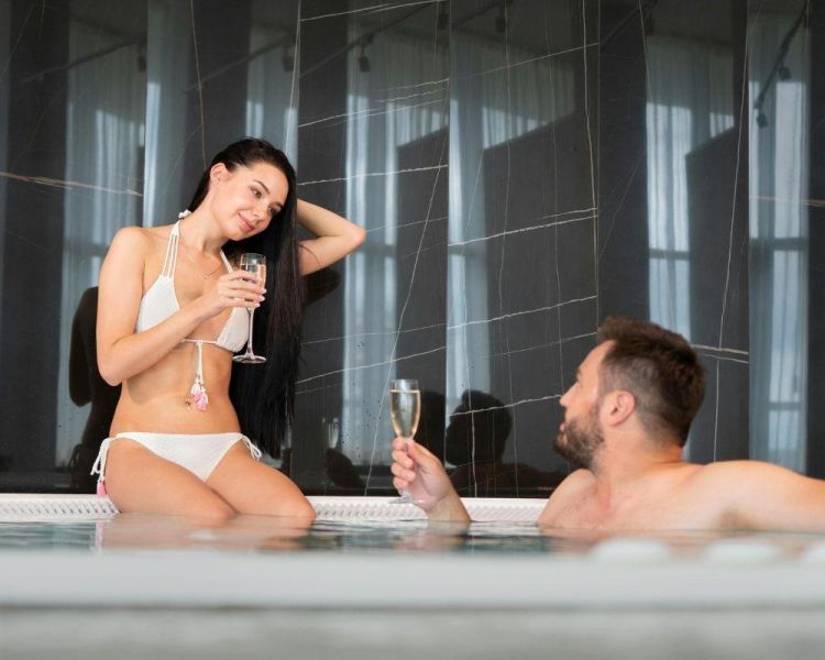 man and woman drinking wine in a jacuzzi ...