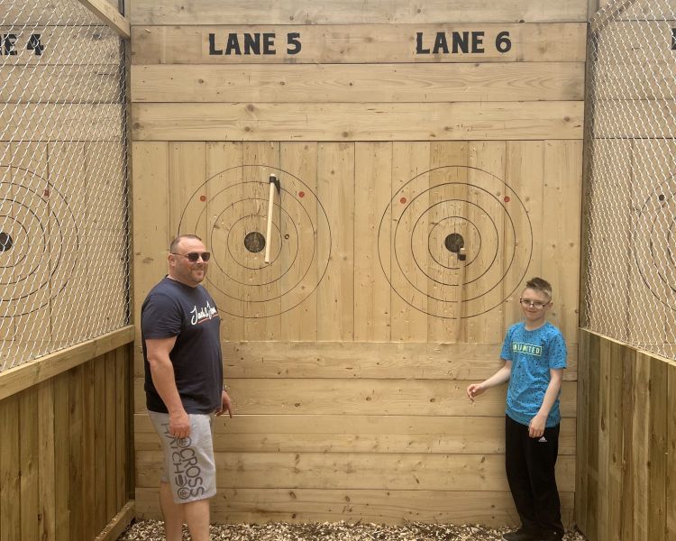 man and young boy posing for photo next to the targets on an axe throwing experience in tunbridge wells in kent