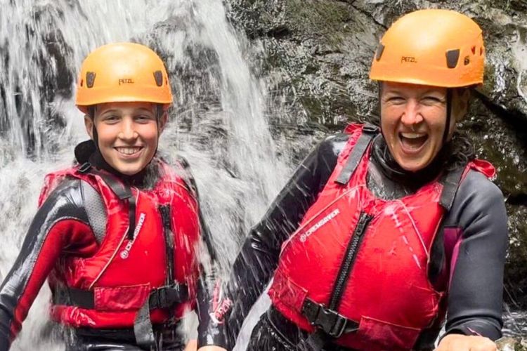 Young boy and woman standing in a waterfall
