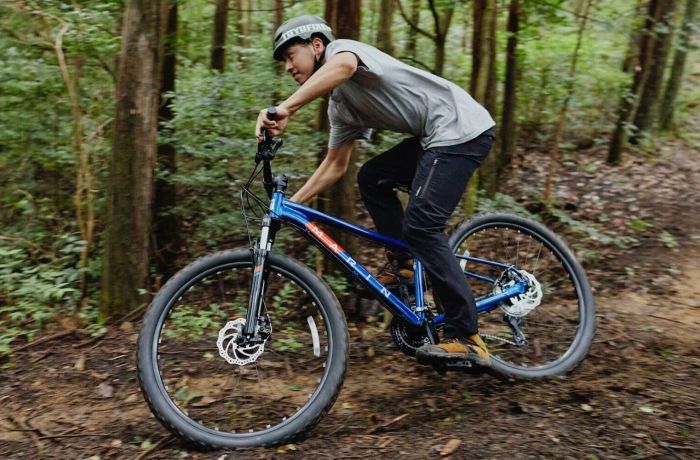 person mountain biking on a muddy track through a forest