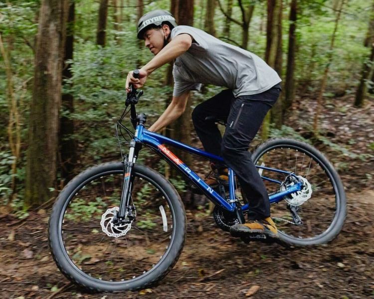 person mountain biking on a muddy track through a forest