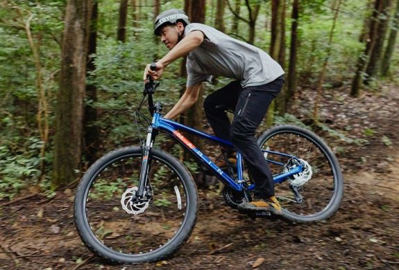 person mountain biking on a muddy track through a forest