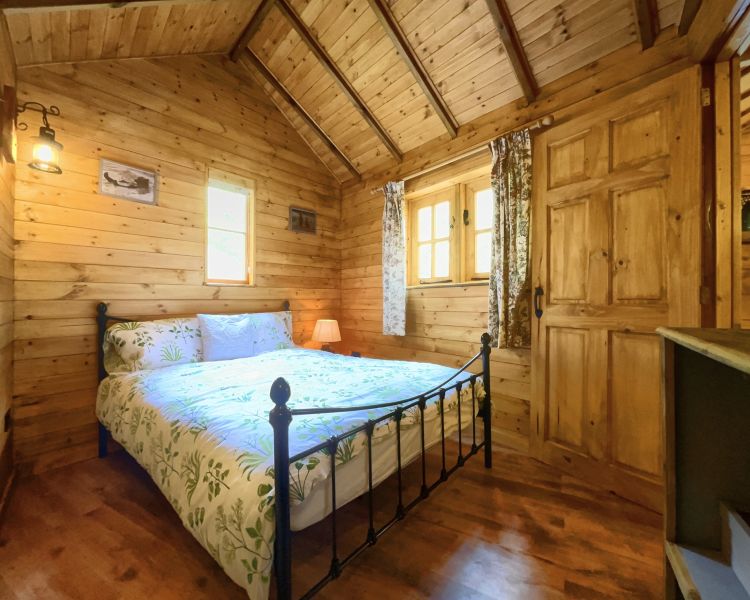 the bedroom with double bed in bears house wooden cabin used for glamping experience in cambridgeshire
