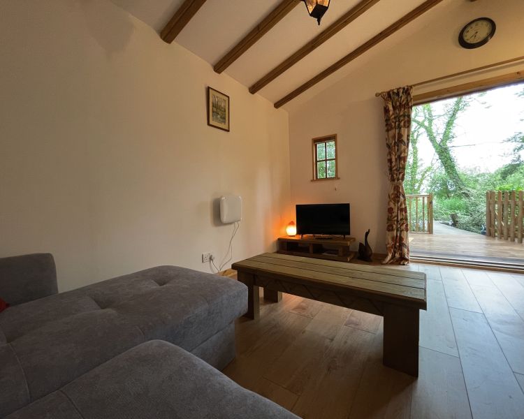 the living room area of lions house wooden cabin with front doors open on glamping experience in cambridgeshire