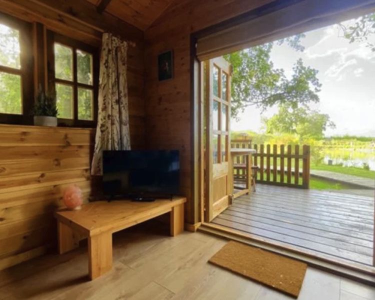 the inside of beavers house wooden cabin with doors open out to the countryside on a glamping experience in cambridgeshire