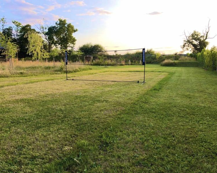 a lawn with a badminton net set up in the grounds of a glamping site in cambridgeshire