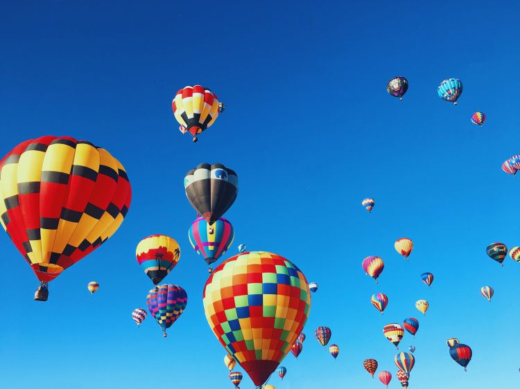 many colourful hot air balloons floating in a bright blue sky