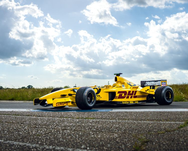 side view of a yellow jordan f1 race car on a race track