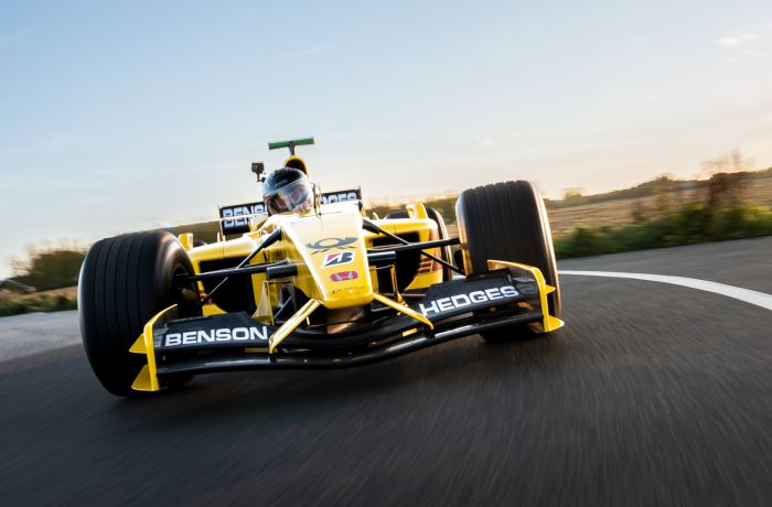 a front view of a yellow and black formula one race car on a race track as part of a driving experience