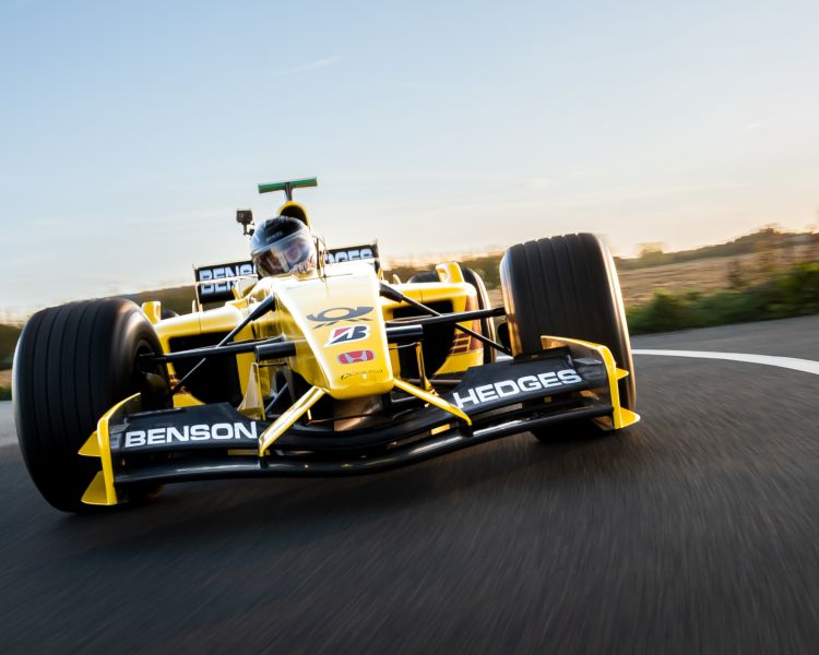 a front view of a yellow and black formula one race car on a race track as part of a driving experience