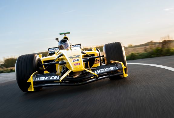 a front view of a yellow and black formula one race car on a race track as part of a driving experience