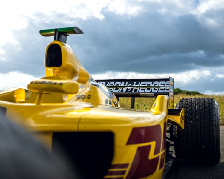 close up shot of the front of a yellow jordan f1 race car with dark clouds overhead