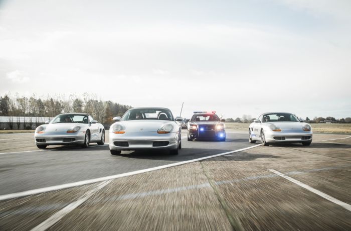 three sports cars and one police car side by side on a race track