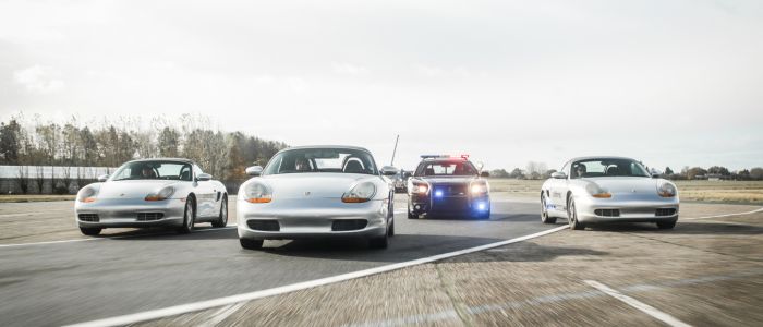 three sports cars and one police car side by side on a race track