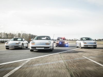 three sports cars and one police car side by side on a race track