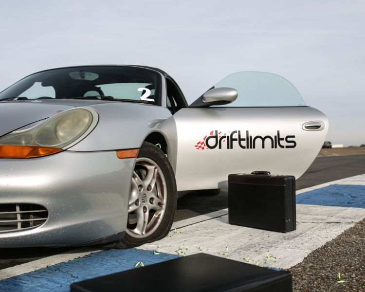 front view of a silver sports car with driver door open and briefcase on the floor