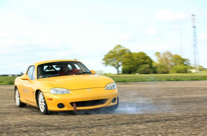 front view of a yellow sports car being driven around a race track