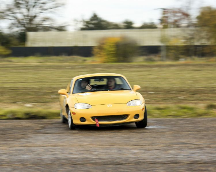 front view of a yellow sports car being driven around a course