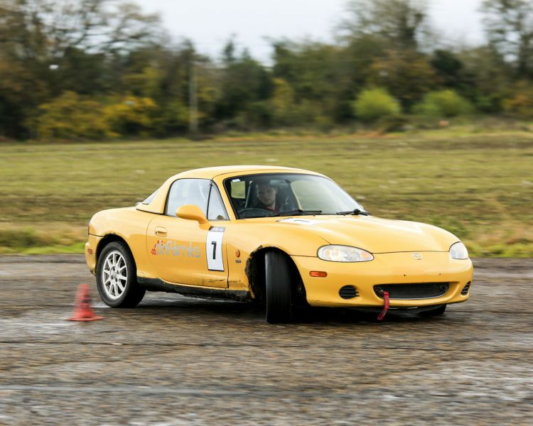 yellow sportscar being driven around a course