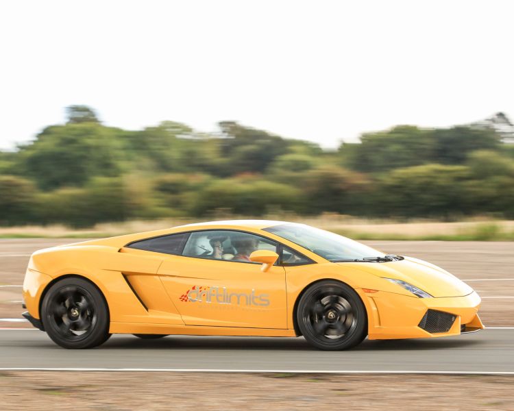 yellow supercar driving on a race track with trees in the background