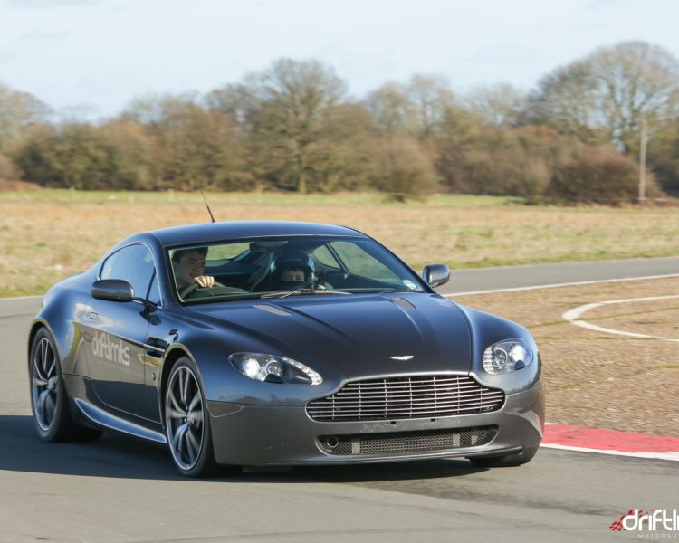 black supercar driving round a bend on a race track on a sunny day
