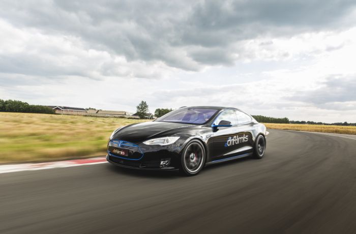 a black tesla driving along a race track going around a bend