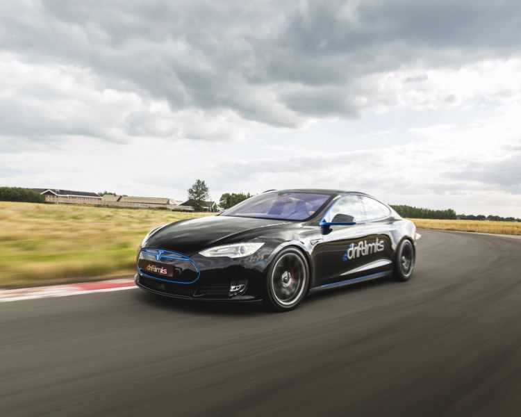 a black tesla driving along a race track going around a bend