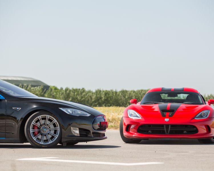 two supercars, a tesla and a viper, side by side on a race track