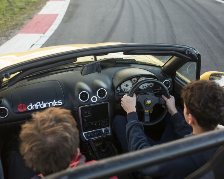 view from the back of a young person learning how to drive a supercar alongside an instructor on a race track