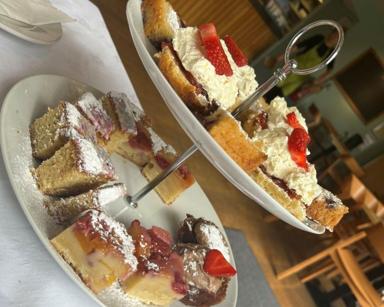 display of afternoon tea cakes and scones on a cake stand on table with white tablecloth