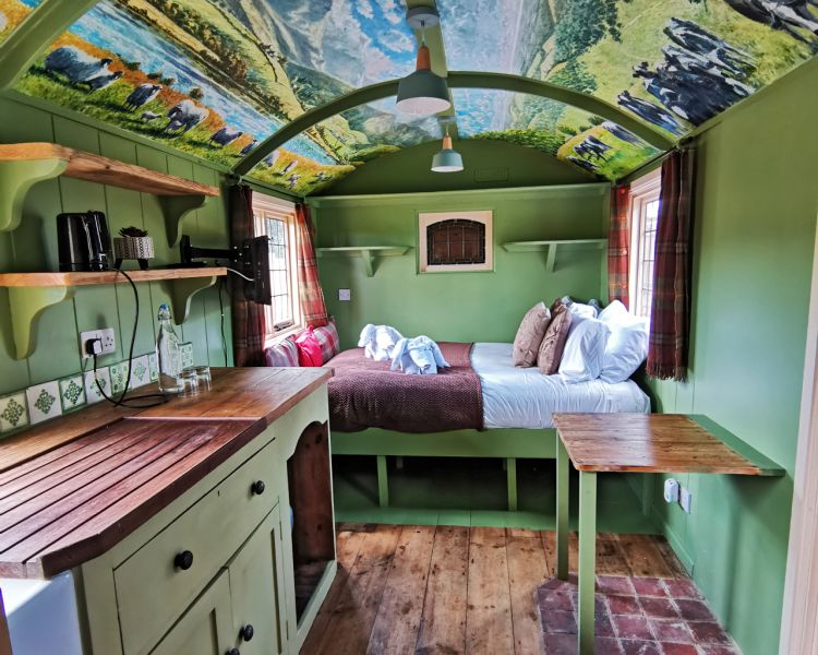 Looking at the bed area from the kitchen inside the shepherds hut used for short stays near stonehenge