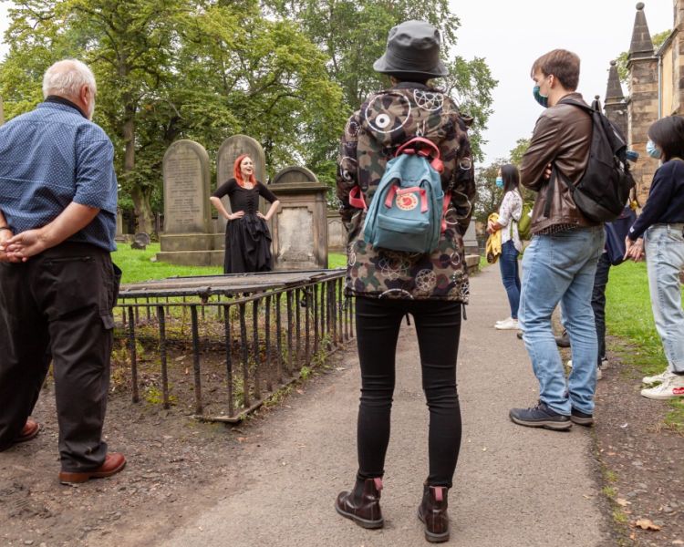 Guide talking to group in a graveyard on a vaults and graveyard walking tour in edingburgh