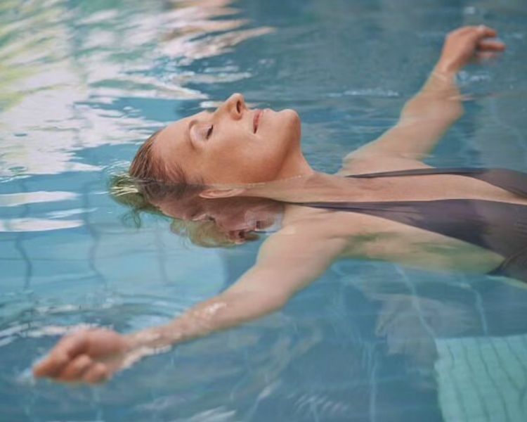 woman floating on her back in a swimming at the natural light spa
