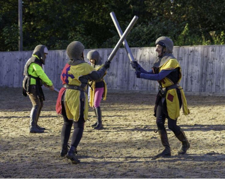 people dressed as medieval knights practicing a sword fight on a jousting experience
