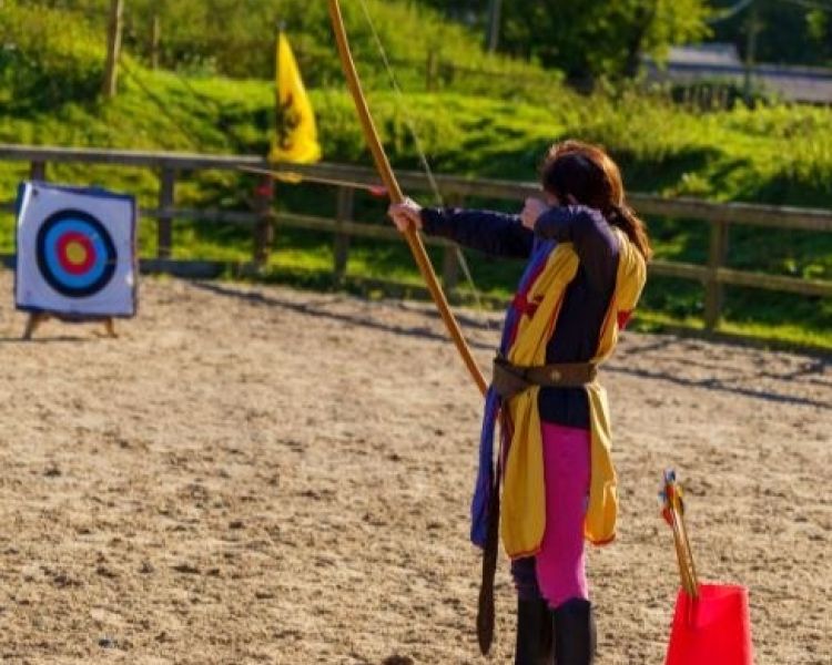 person dressed as a medieval knight practicing archery with a bow and arrow on a jousting experience