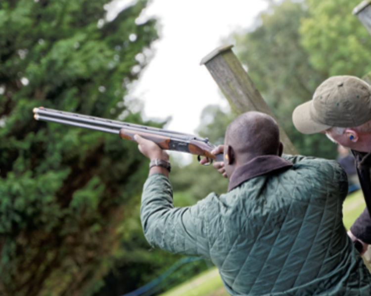 man pointing shotgun to the sky with instructor looking on as part of clay pigeon shooting experience
