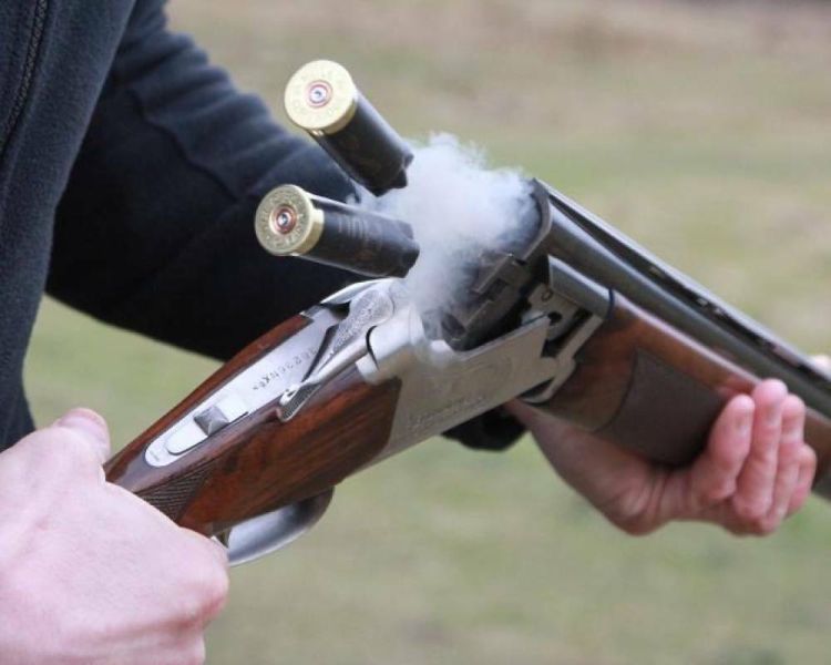 close up of a shotgun held with two hands and two cartridges being ejected
