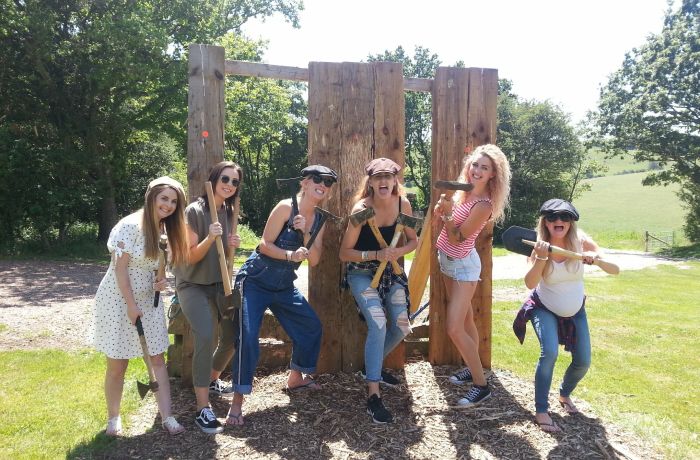 group of women posing in front of wooden boards holding axes as part of an axe throwing experience