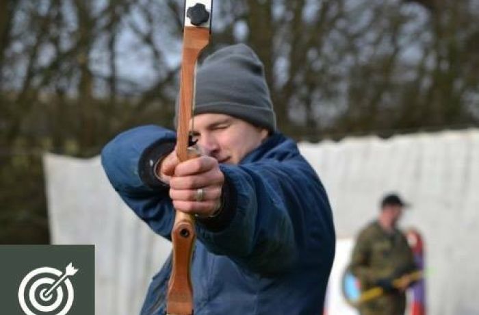 man holding a bow and arrow aiming towards the camera as part of an archery experience