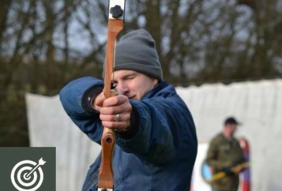 man holding a bow and arrow aiming towards the camera as part of an archery experience