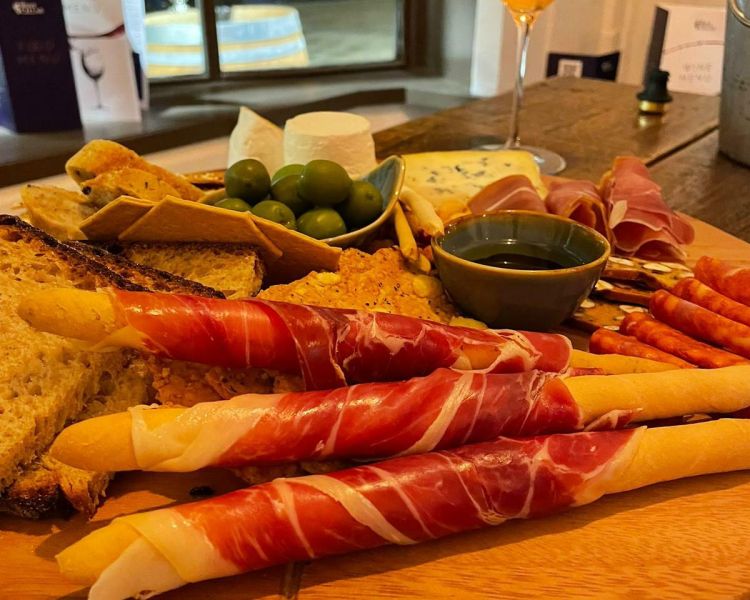 close up shot of a sharing board of meats and cheeses with a glass of wine at the wine cellar in brighton