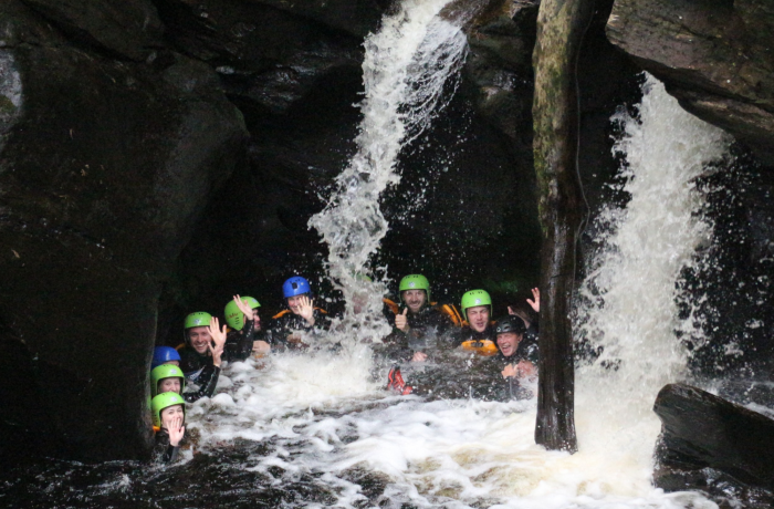 group of people in water at the bottom of a canyon on a canyoning experience in scotland